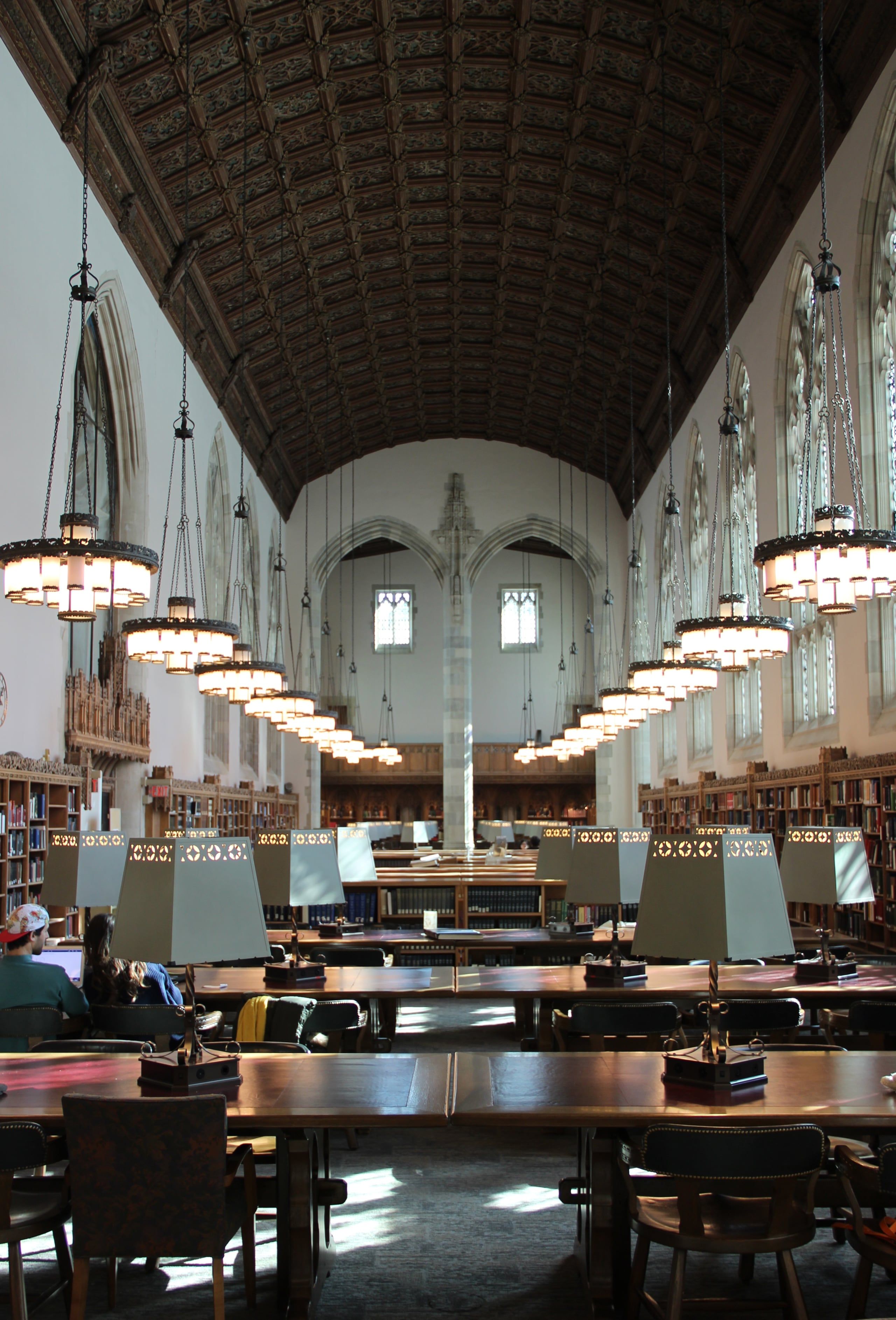 The Starr Reading Room in Sterling Memorial Library at Yale, its long tables lit by lamps under a vaulted ceiling